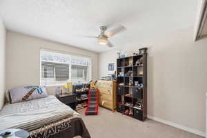Bedroom with light carpet, ceiling fan, and a textured ceiling