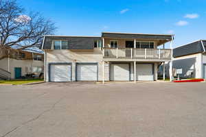 View of front of house with mansard roof, roof with shingles, driveway, an attached garage, and a balcony