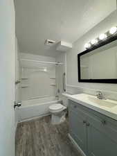 Full bath featuring vanity, shower / washtub combination, a textured ceiling, and dark wood-style flooring