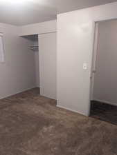 Unfurnished bedroom with a closet and dark colored carpet