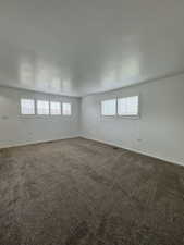 Empty room with healthy amount of natural light and dark colored carpet