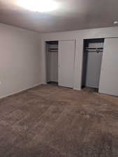 Unfurnished bedroom featuring two closets and carpet flooring