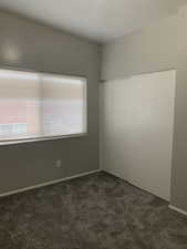 Spare room with dark carpet and baseboards