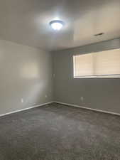 Spare room featuring baseboards and dark carpet