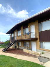 Rear view of property featuring brick siding, stairway, board and batten siding, and a balcony