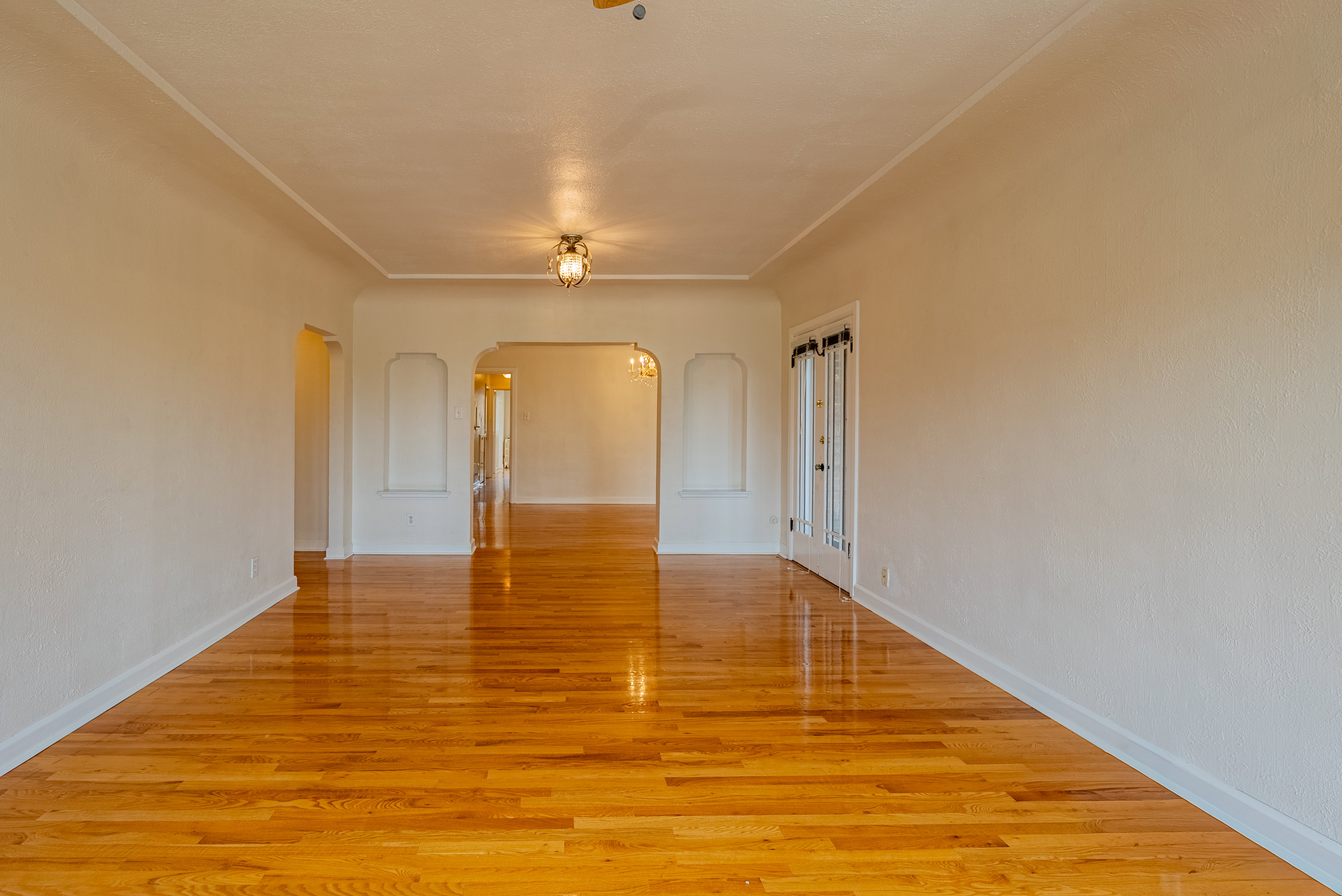 Hardwood flooring extending throughout, featuring a coved ceiling, baseboards, and decorative wall niches