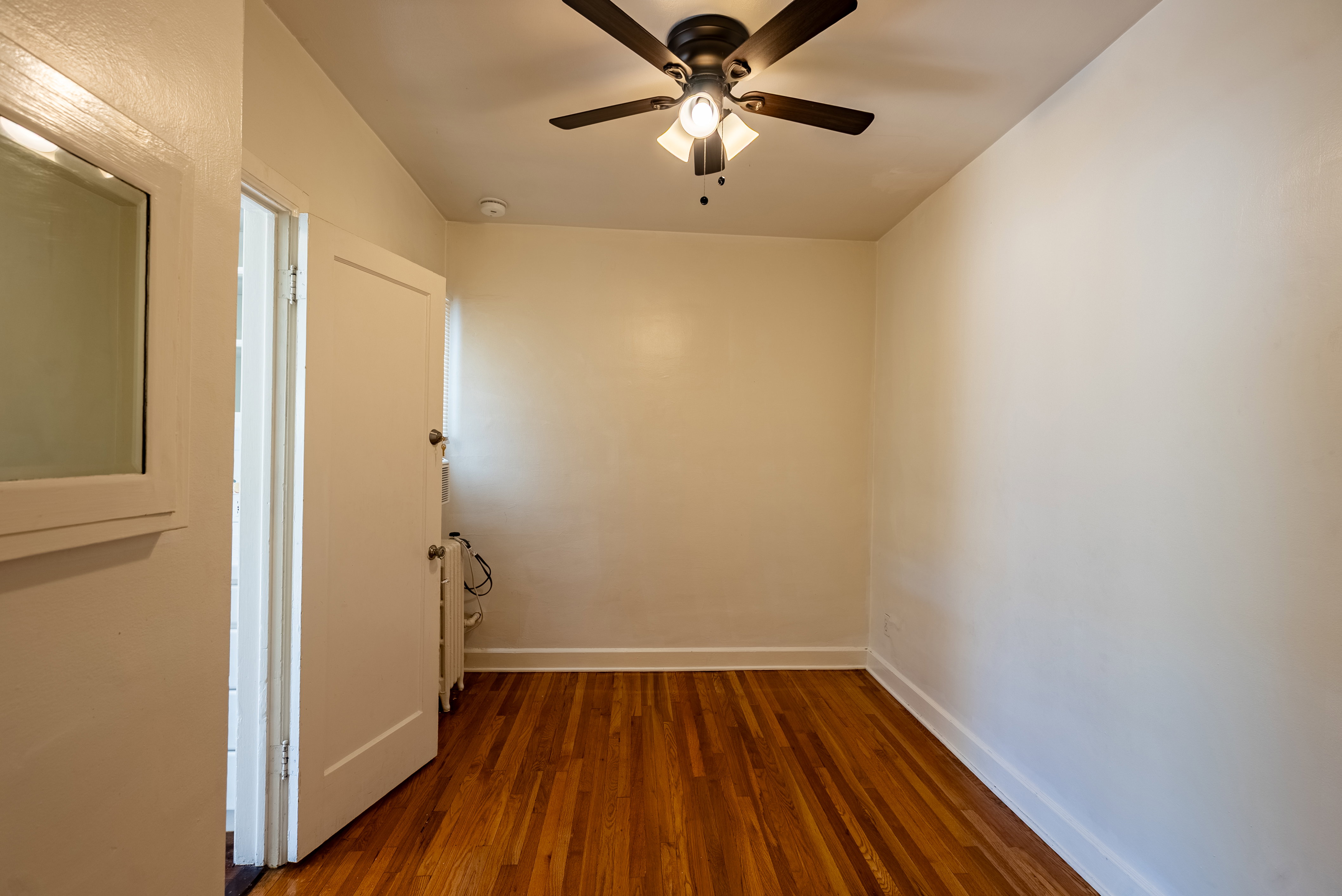Room featuring wood-finish flooring, white baseboards, and a ceiling fan with integrated lighting