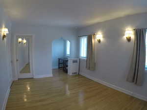 Apt # 15 > Unfurnished room with arched walkways and light wood-style floors