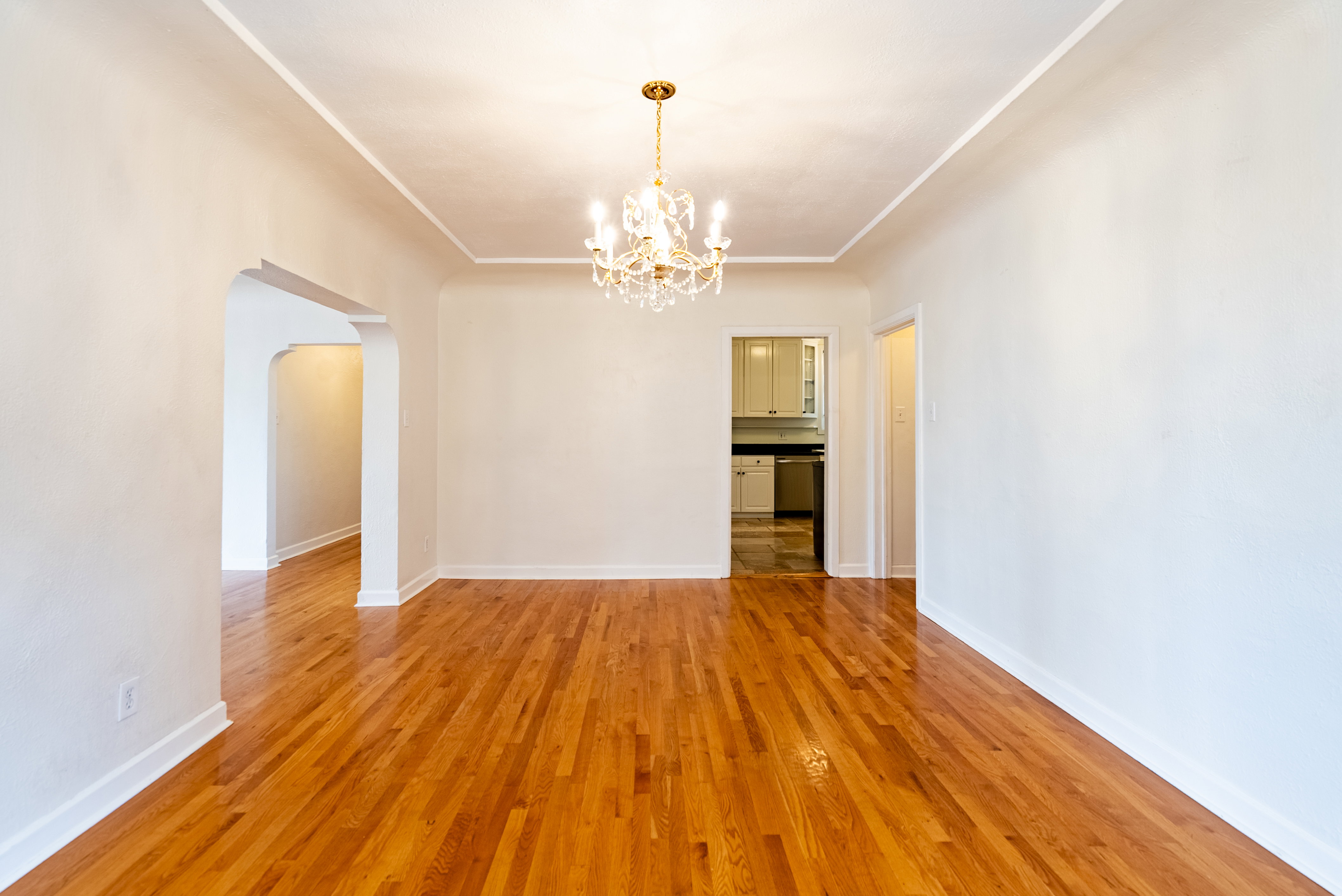 Hardwood flooring throughout featuring a decorative chandelier and arched doorways