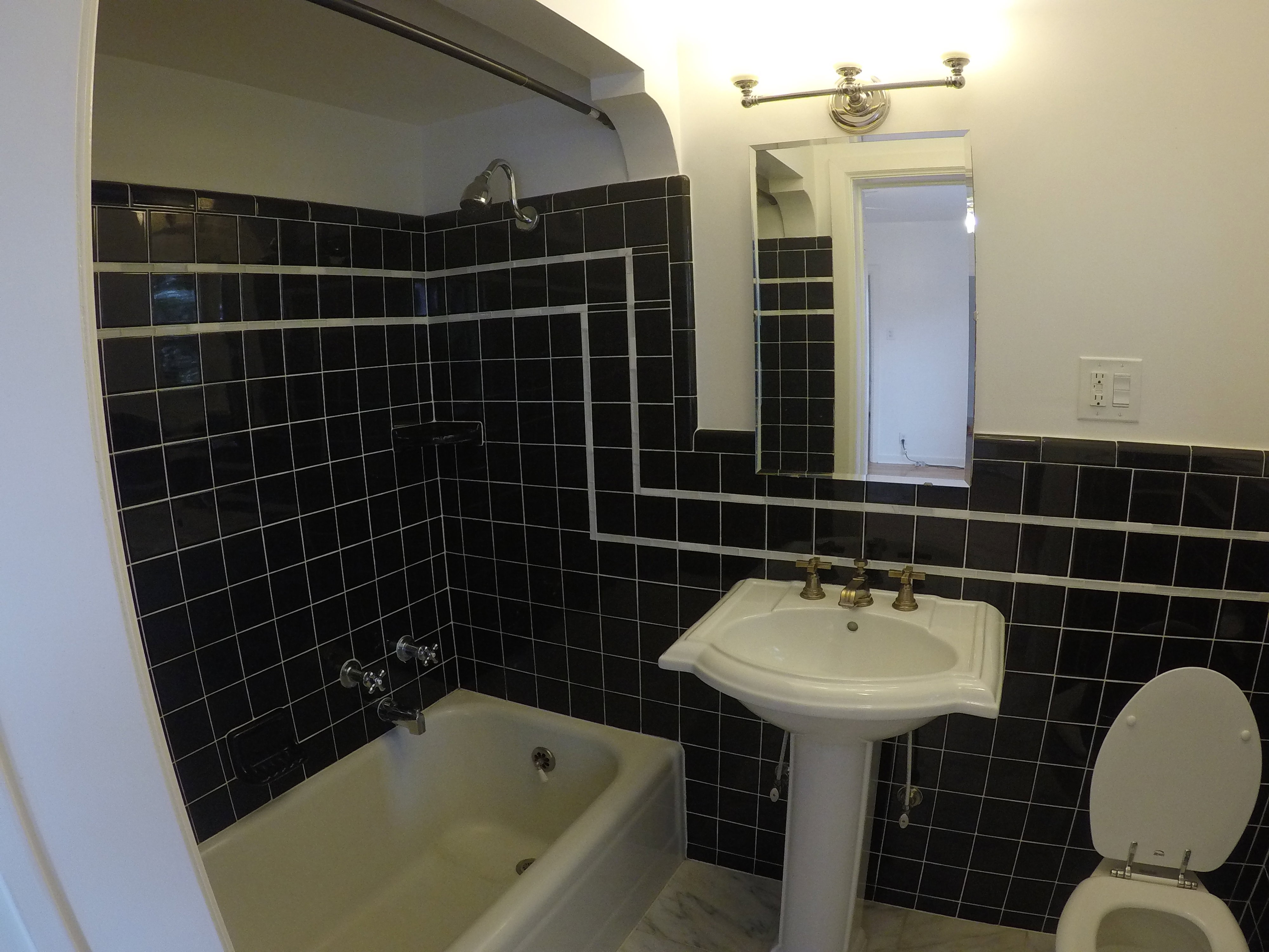 Apt #2 >  Bathroom featuring tile walls,  shower combination, and wainscoting