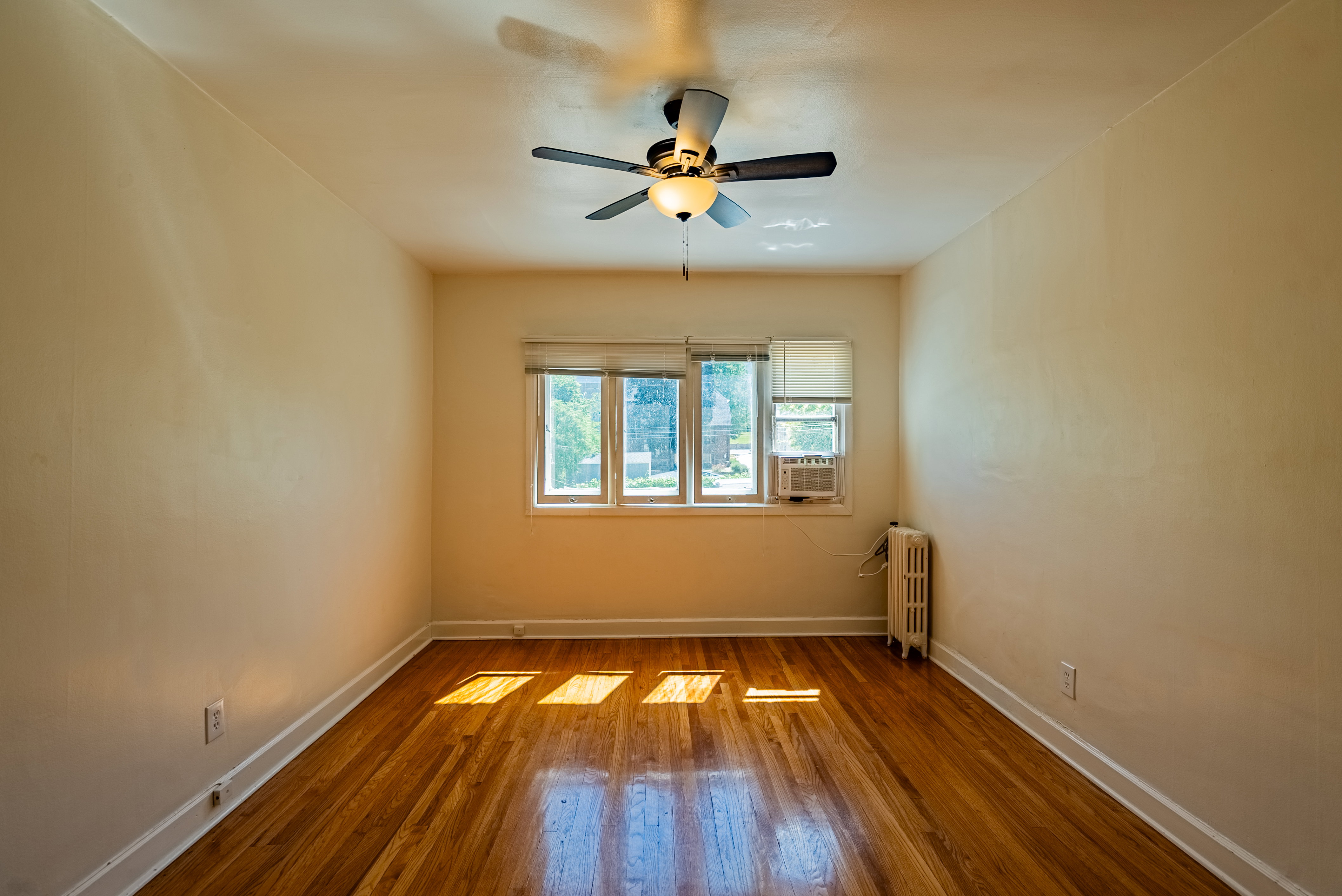 Spacious room featuring wood-finish flooring, white baseboards, and neutral wall tones