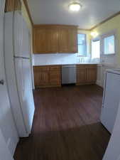 Apt # 4 >  Kitchen with white appliances, light countertops, dark wood-style flooring, crown molding, and brown cabinetry