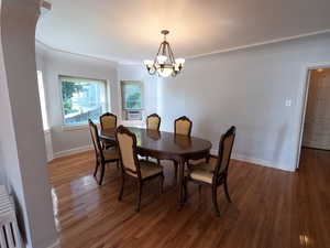 Apt # 1  Dining space featuring radiator heating unit, wood finished floors, and a chandelier