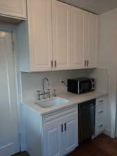 Apt # 16 > Kitchen featuring white cabinetry, dishwasher, black microwave, dark wood-style flooring, and light stone countertops
