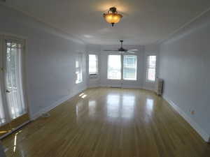 Apt # 15 > Unfurnished dining area featuring wood-type flooring, healthy amount of natural light, and radiator