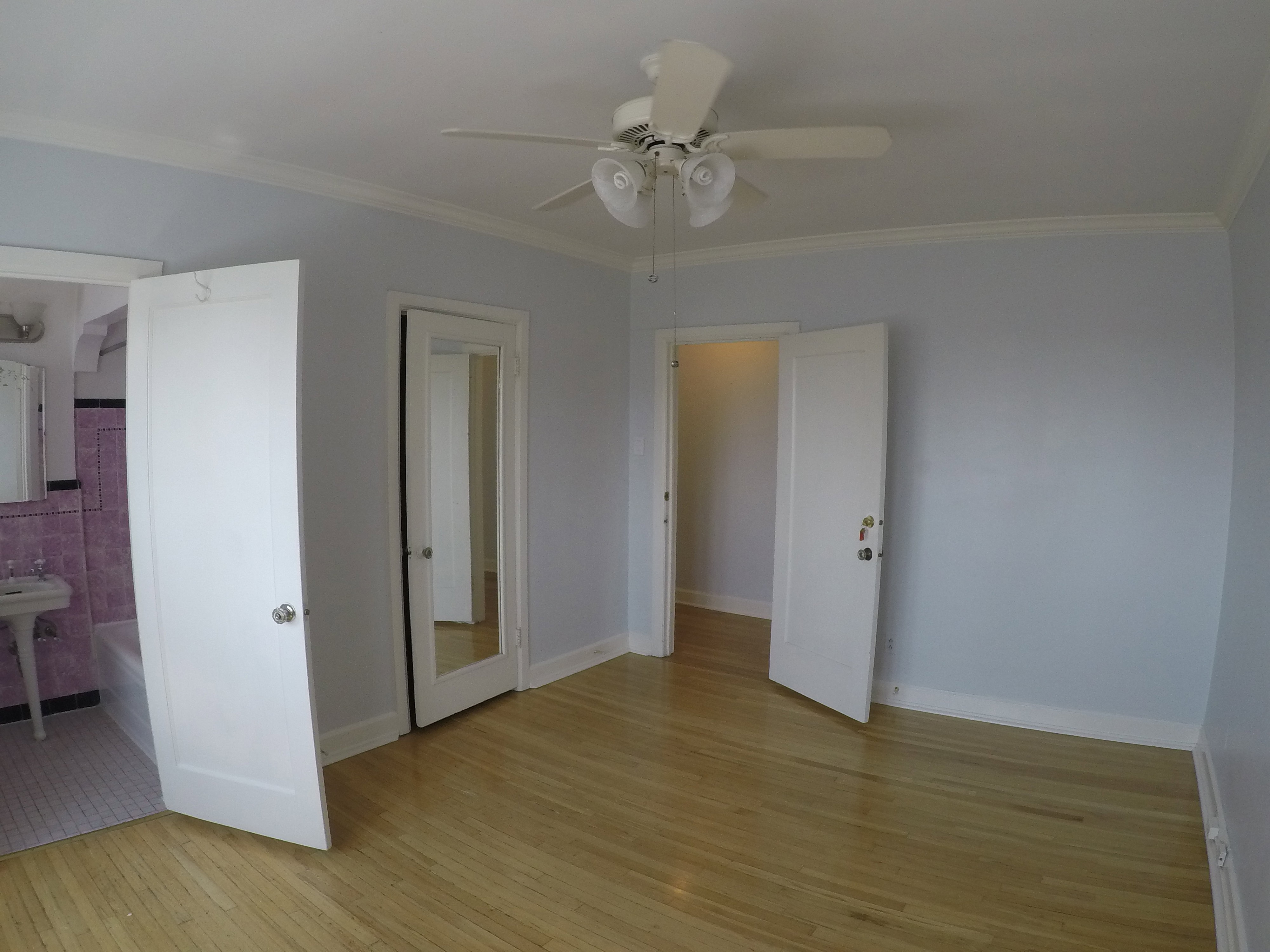 Apt # 15 > Unfurnished bedroom with light wood-style flooring, ornamental molding, ceiling fan, and connected bathroom