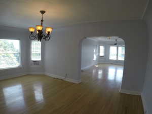 Apt # 15 > Unfurnished room featuring arched walkways, plenty of natural light, and wood finished floors