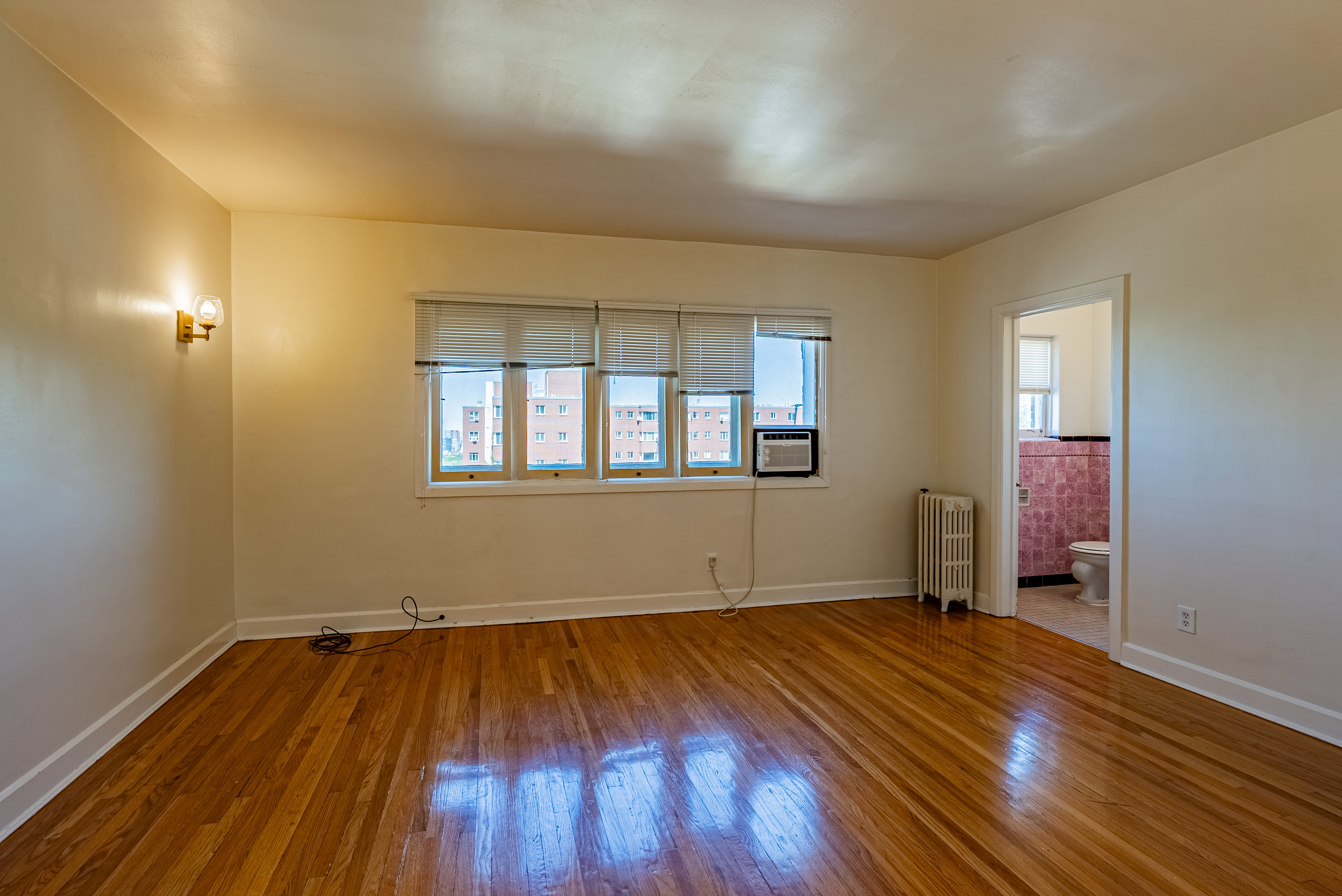 Bright interior space featuring wood-finish flooring, white baseboards, and a wall-mounted sconce