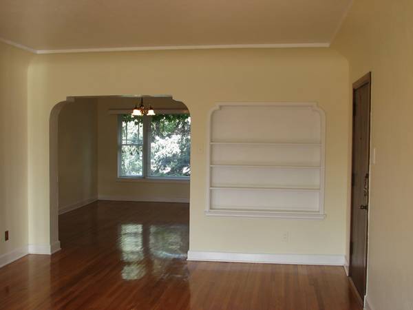 Apt # 11 > Unfurnished room featuring dark wood-style flooring, arched walkways, built in features, a chandelier, and crown molding