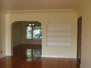 Apt # 11 > Unfurnished room featuring dark wood-style flooring, arched walkways, built in features, a chandelier, and crown molding