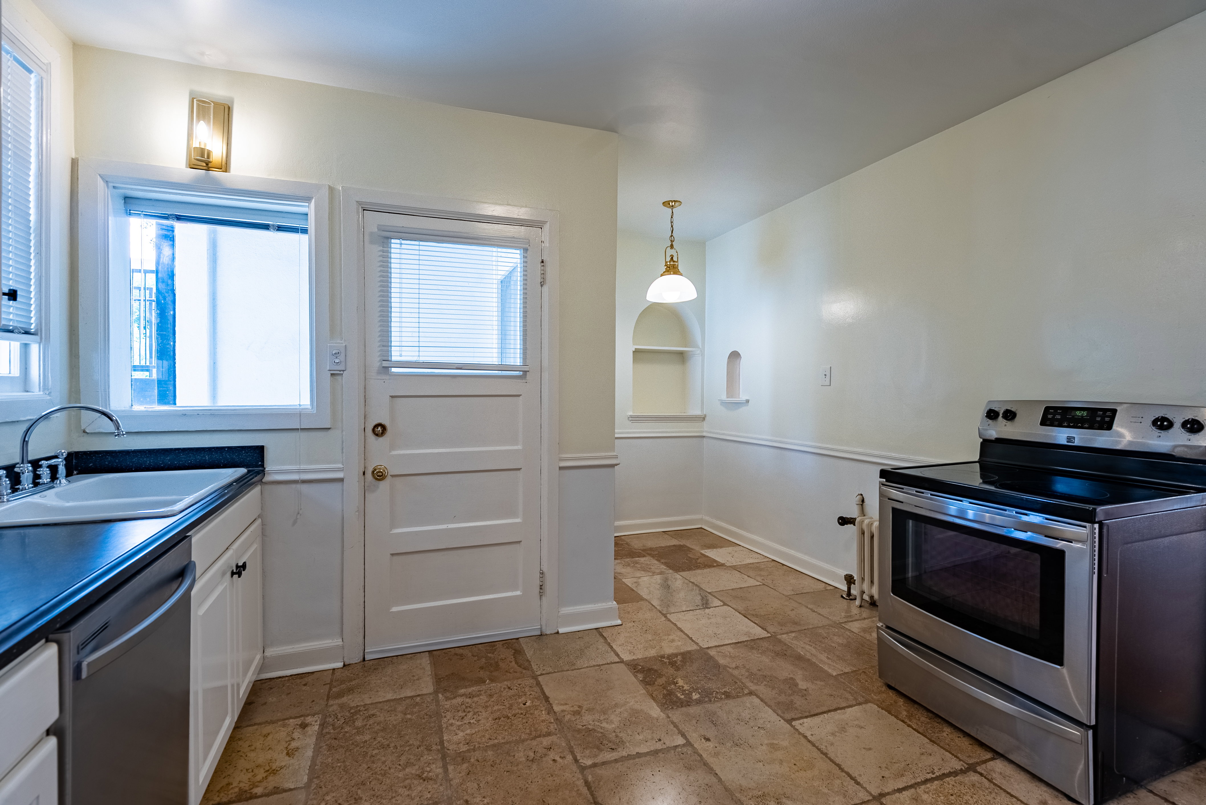 Kitchen featuring a stainless steel range, a stainless steel dishwasher, white cabinetry, dark countertops, and neutral-toned floor tiling