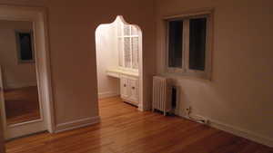 Apt # 12 >Unfurnished bedroom featuring radiator and light wood-style floors
