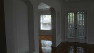 Apt # 10 > Foyer featuring arched walkways, french doors, and dark wood-style flooring