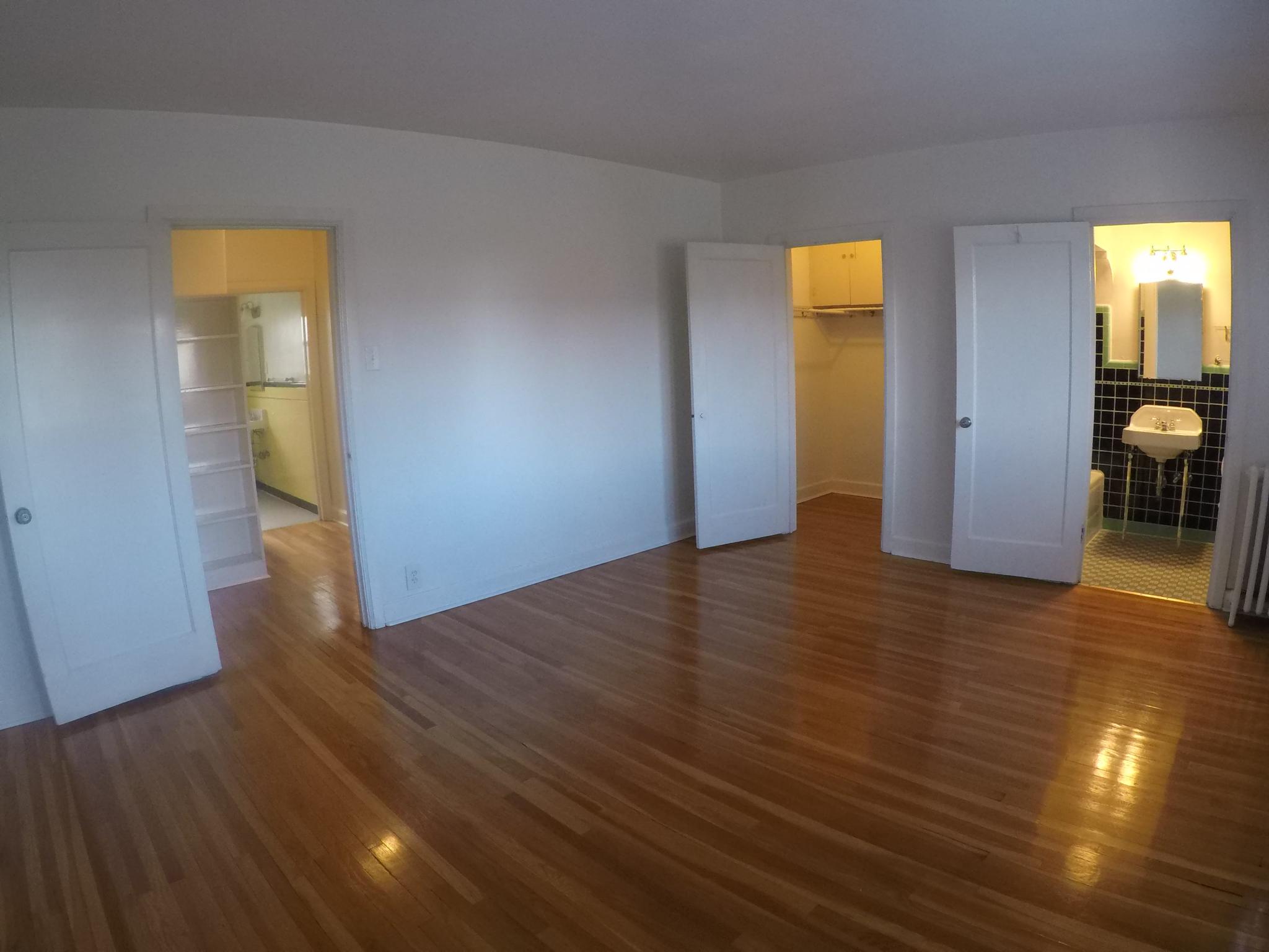Apt # 4 >  Unfurnished bedroom featuring dark wood-style flooring, connected bathroom, a walk in closet, and radiator