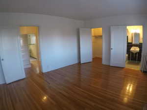 Apt # 4 >  Unfurnished bedroom featuring dark wood-style flooring, connected bathroom, a walk in closet, and radiator