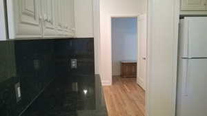 Apt # 1 Kitchen featuring freestanding refrigerator, light wood-style flooring, and white cabinets