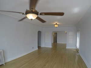 Apt # 15 > Spare room featuring arched walkways, radiator heating unit, light wood finished floors, and built in features