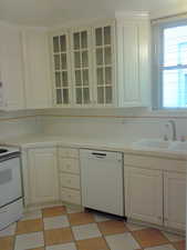 Apt #2 >  Kitchen with light flooring, white appliances, and white cabinets