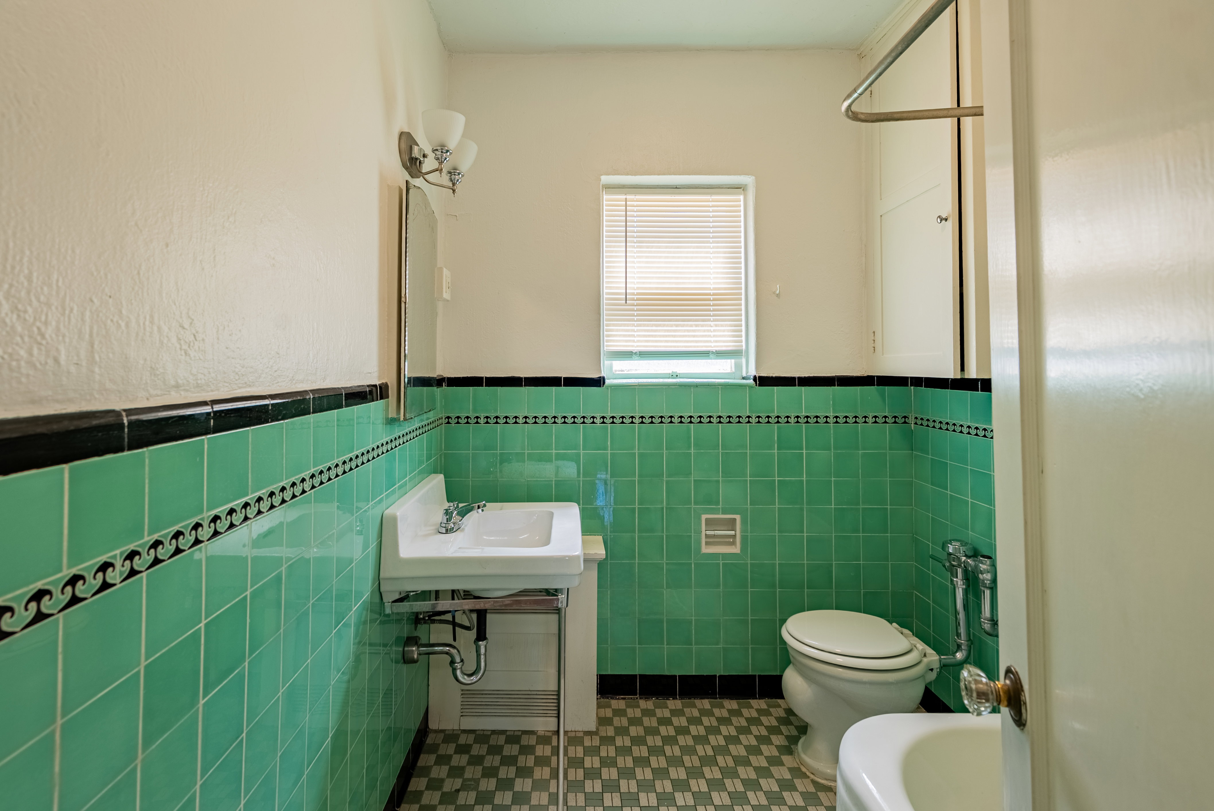 Bathroom featuring vibrant green tile walls with black trim and a decorative border