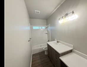 Full bath featuring vanity, tub / shower combination, and dark wood-type flooring