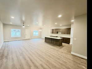 Kitchen with a kitchen island with sink, open floor plan, recessed lighting, light wood-style flooring, and a chandelier