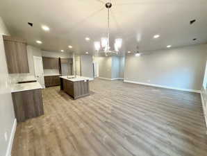 Kitchen featuring a center island with sink, open floor plan, hanging light fixtures, a chandelier, and recessed lighting