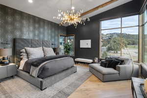 Bedroom featuring wood finished floors, multiple windows, a chandelier, and lofted ceiling