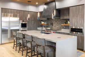 Kitchen featuring a breakfast bar, light wood-style floors, stainless steel appliances, pendant lighting, and open shelves