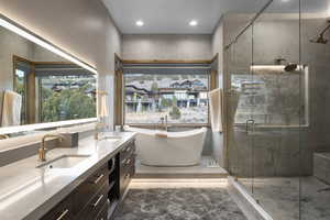 Bathroom featuring double vanity, a freestanding bath, a shower stall, and recessed lighting