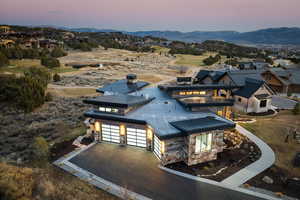 View of front facade featuring driveway, a garage, stone siding, a mountain view, and a patio