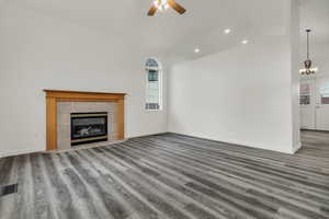 Unfurnished living room with a fireplace, wood finished floors, ceiling fan, recessed lighting, and a chandelier