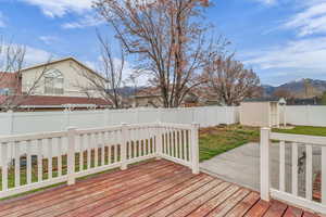 Wooden deck with a fenced backyard, a storage unit, and a mountain view
