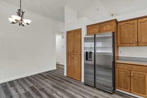 Kitchen featuring stainless steel fridge with ice dispenser, brown cabinets, decorative light fixtures, and crown molding
