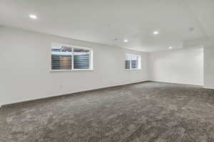 Empty room featuring healthy amount of natural light, recessed lighting, and dark carpet