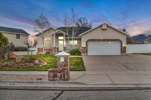 View of front facade with brick siding, concrete driveway, and an attached garage