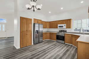 Kitchen with plenty of natural light, light countertops, brown cabinets, stainless steel appliances, and vaulted ceiling