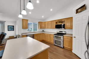 Kitchen featuring appliances with stainless steel finishes, double oven, maple cabinets,, vaulted ceiling, and solid surface countertops