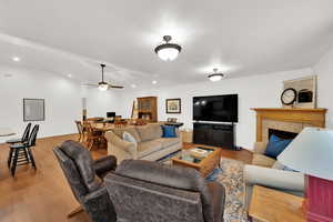 Living area with vaulted ceiling, LVP floors, a tiled fireplace, and recessed lighting