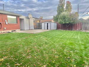 Fenced backyard featuring a shed and a patio area