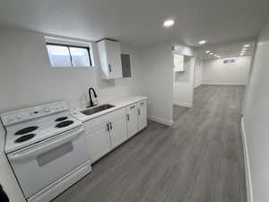 Kitchen featuring white range with electric cooktop, white cabinetry, light wood finished floors, electric panel, and recessed lighting